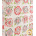 Close up of a cream quilt with abstract roses made of layered shades of pink fabric flat against a wall