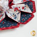 Close up of a flower shaped table topper with central opening with a small jar and patriotic decor in the background. Topper is made of crisp white, red and navy blue fabrics with multicolor florals.