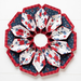 Flower shaped table topper with central opening isolated on a white background. Topper is made of crisp white, red and navy blue fabrics with multicolor florals.