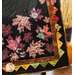 Close up photo of the Autumn Allure quilt showing applique leaf details and a zig zag pattern sewn into the border