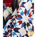 Photo of a large patriotic quilt draped in front of a dark grey arm chair with red white and blue flowers in a white vase