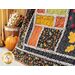 Close up of one corner of the large autumn themed quilt with a basket of matching fabrics and pumpkin in the background