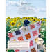 A scene of a woman holding a quilt stretched out behind her back in a sunflower field