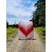 Someone holding a red and cream quilt on a dirt road on a bright and sunny day