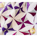 Close up of draped quilt with white background fabric and purple pinwheels