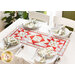 A top down image of a white table with four place settings with white plates and matching strawberry themed napkins in silver napkin rings and a red and white table runner in the center.