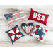 A top-down photo of a collection of five patriotic themed pillows on a white wooden countertop