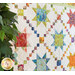 Colorful quilt with diamonds all over with traditional style sawtooth stars made with floral fabrics from the Wild Blossoms collection with a green houseplant in the foreground