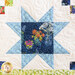 close up of one block showing a sawtooth star made with blue floral and textured fabrics on a white background