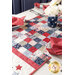 close up of patchwork pattern in the center of the patriotic table runner with the edges of four place settings all around and a patriotic centerpiece on the right side