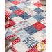 close up of patchwork pattern in the center of the patriotic table runner with the edge of a place setting to the left, just out of frame