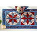 Red, white and blue table runner in the center of a white table with a patriotic themed centerpiece