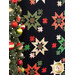 Close up of Merry & Bright Quilt showing a cluster of starbursts made with black, red, green, and cream fabrics with Christmas motifs and metallic accents featuring a decorated Christmas tree in the foreground.