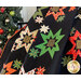 Close up of Merry & Bright Quilt draped in front of a decorated Christmas tree, showing fabric detail which features Christmas motifs and metallic accents
