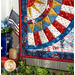 Angled close up photo of finished patriotic quilt square on a craft hanger sitting on a brown countertop with a white paneled wall in the background and patriotic decor and plants to one side.