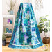 Image of a draped blue, green, and purple quilt with a white shelf, houseplant, and matching decor in the background.