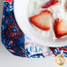Close up of one edge of bowl cozy showing detail of patriotic fabrics from the Fired Up collection and a white bowl inside holding strawberries and whipped cream