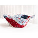 A red, white, and blue bowl cozy made with patriotic fabrics from the side on a white countertop with a white paneled wall behind.