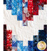 A close up photo of a red, white and blue quilt with a large zig zag pattern made with strips of batik fabrics