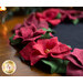 Close up image of the floral edge of the wool table topper showing layered wool to form red petals with green leaves on a black background