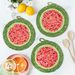 Set of 3 round Watermelon Trivets made with pink and green batiks on a white countertop with lemons, daisies, a bowl decorated to look like an orange, and wooden spoons on either side