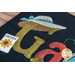 Close up of black wool mat showing applique detail of seed packet and sun hat on the 