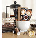 brown, black, and cream coffee related fabrics stacked in and around a coffee mug with coffee beans and a french press behind