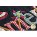 Close up of black wool mat showing applique detail of a festive pinwheel coming from the 