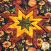 Close up of folded star hot pad for November, featuring pumpkins, sunflowers, and bright yellow textures with plaid accents on a white countertop