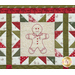 Close up of one quilt block showing fabric and stitching detail with an embroidered image of a gingerbread man cookie