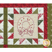 Close up of one quilt block showing fabric and stitching detail with an embroidered image of a winter wreath with a bow