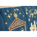 Close up photo of a large blue bench pillow embellished with decorative stitching in a nativity scene with twinkling lights