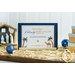 Photo of a collectible sewing box from Kimberbell for the Nativity Bench Pillow atop a farmhouse style cabinet with hay, lights, and small nativity decor all around with a white paneled wall in the background