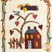Photo of a small quilt hanging on a brown paneled wall featuring a house, tree bearing hearts, an angel flying overhead, surrounded by a floral vining border.