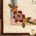 Close up photo of one corner of the quilt showing stitching detail and an applique flower.