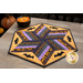 Photo of a Halloween themed table topper in the center of a gray table with autumn decor in the background and a bowl of candy corn on the table.