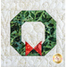 Close up photo of a quilt block featuring a wreath with a red bow made out of christmas themed batik fabrics