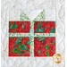 Close up photo of a quilt block featuring a wrapped gift box with a bow made out of christmas themed batik fabrics