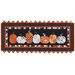 Photo of a Halloween themed table runner made with black, orange, and white fabrics with points along the top and bottom and a row of pumpkins in the center, isolated on a white background
