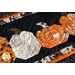 Close up photo that shows fabric detail and stitching of a Halloween themed table runner made with black, orange, and white fabrics with a row of pumpkins in the middle.