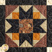 Close up of a single quilt block featuring a traditional pattern made with brown, orange, and black fabrics