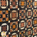 Close up of the center of the quilt featuring traditional quilt block patterns made with brown, orange, and black fabrics