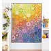 Photo of a rainbow colored floral quilt hanging flat on a white paneled wall with a white bench, lattice, and shelf, and floral decor all over