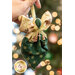 Close up photo of a pocket angel ornament made with the Stof Christmas 2023 fabric collection being held by the ribbon in someone's hand with a decorated and lit Christmas tree in the background