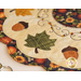 Close up photo of an applique leaf, acorns, and embroidery detail on an autumn-themed table topper
