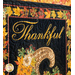 Close up photo of the top of the Fall Inclination panel quilt showing panel details featuring fall leaves, metallic accents, the top of a cornucopia, and the word 