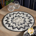 Photo of a black, white, and grey table topper on a brown wooden table with a pair of stemless wine glasses in the background