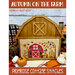 Front of Autumn on the Farm pattern, showing an example of the completed autumnal farm cross stitch, displayed on a wooden barn frame, surrounded by pumpkins and fabric
