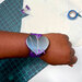 purple slap band with silver magnetic heart with some pins attached, on a person's wrist, on top of a cutting mat and half completed project