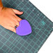 purple silicone heart cutting mat scrubber being used on a mat by a person wearing a sapphire ring